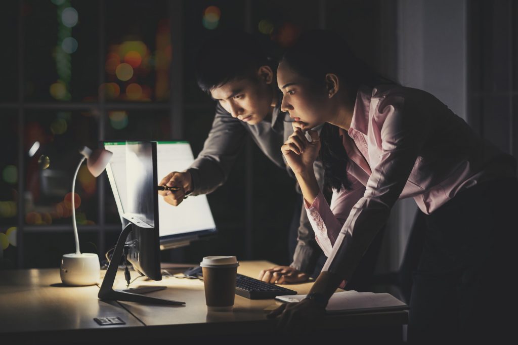 Asian businesswoman and businessman working hard late together with technology computer in office